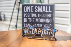 A quote about positive thinking and an eyeglass above a wooden table