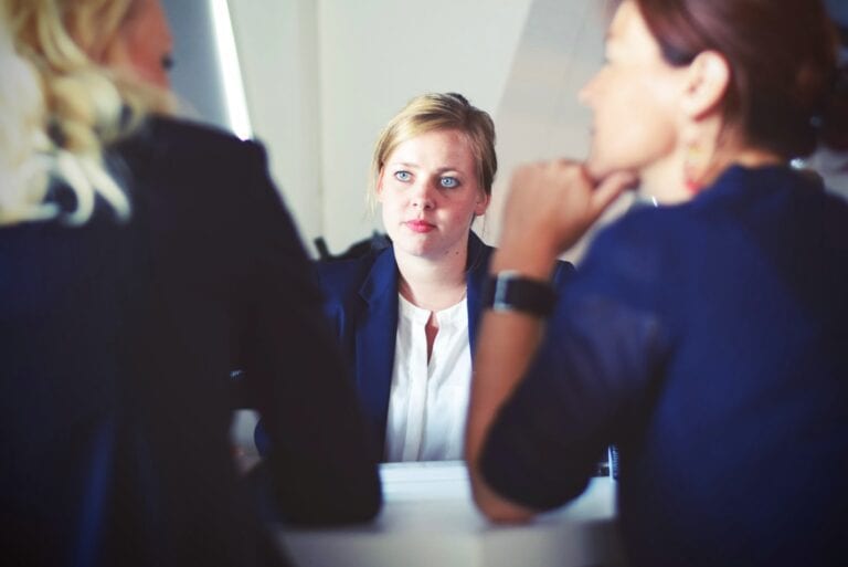 Salary Negotiation tips: two brown haired female interviewers face another blonde female applicant