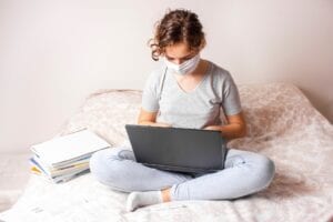 student with mask is preparing her statement of purpose on laptop