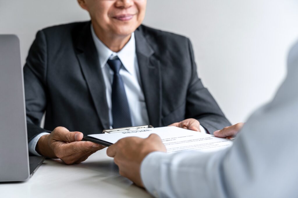 Senior Committee Manager Reading A Resume During A Job Interview