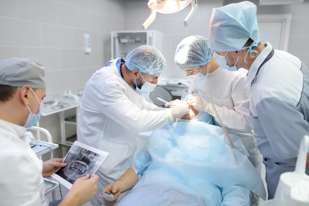 Dental Surgeon In The Operating Room With Externs Assisting 