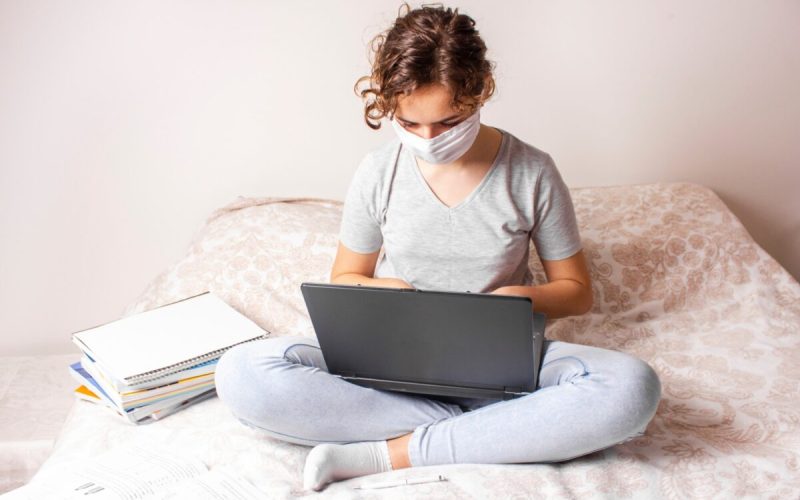 student with mask is preparing her statement of purpose on laptop