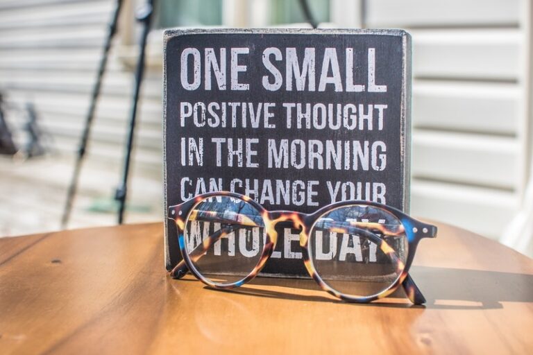 A quote about positive thinking and an eyeglass above a wooden table