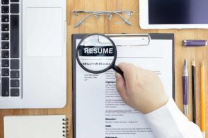How to write a narrative resume: A hand holding a magnifying glass over a narrative resume sample
