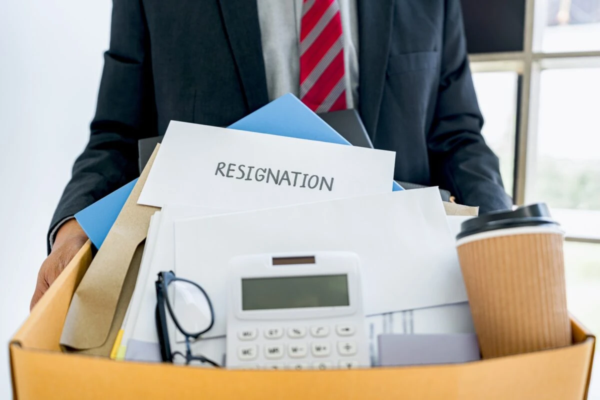 employee carrying all his personal belongings into a brown cardboard box with his resignation letter