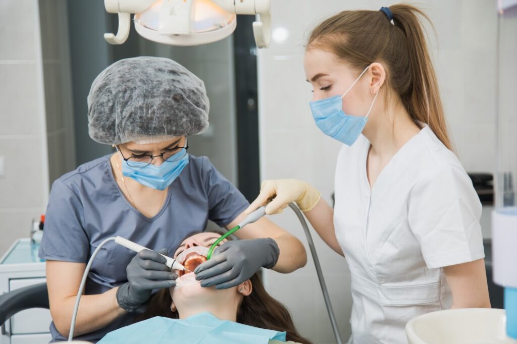 A Dental Assistant And A Dentist Performing A Treatment On A Patient