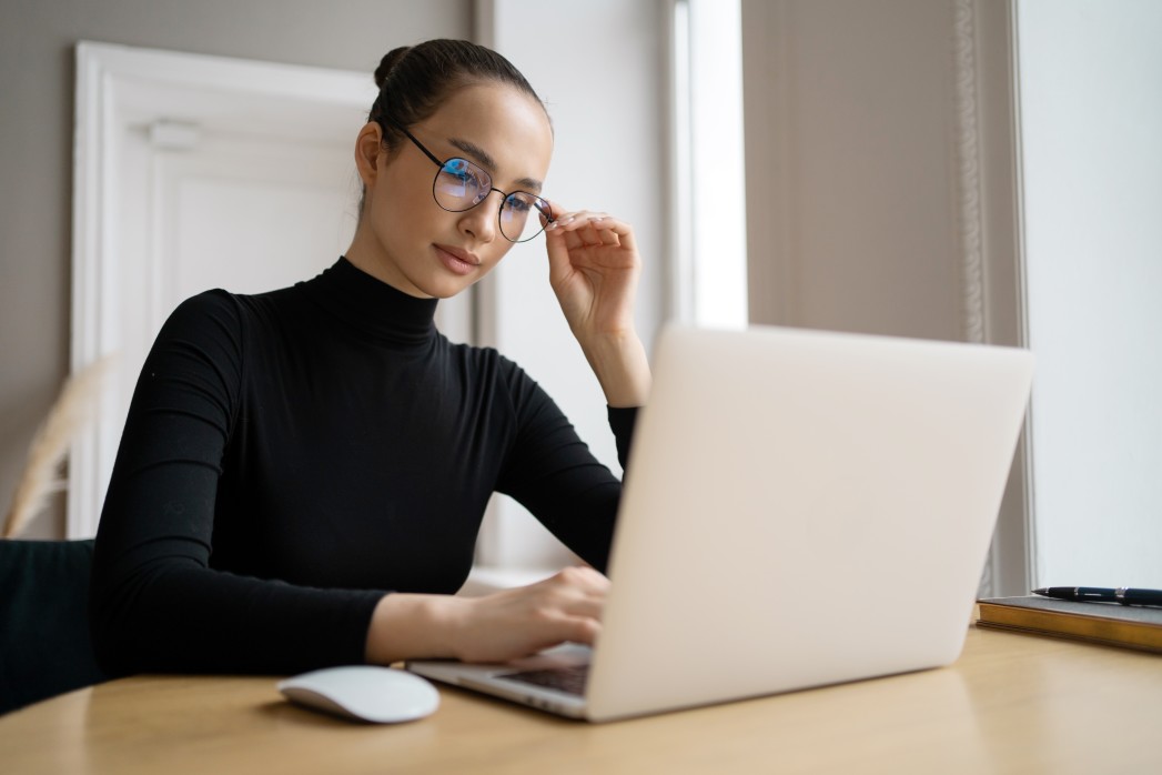 A Woman Writing Social Media Manager Resume On Laptop