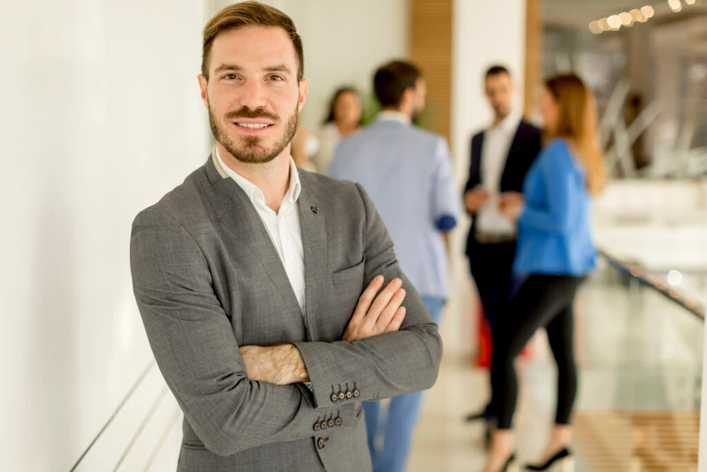ceo posing while his employees are discussing in the background