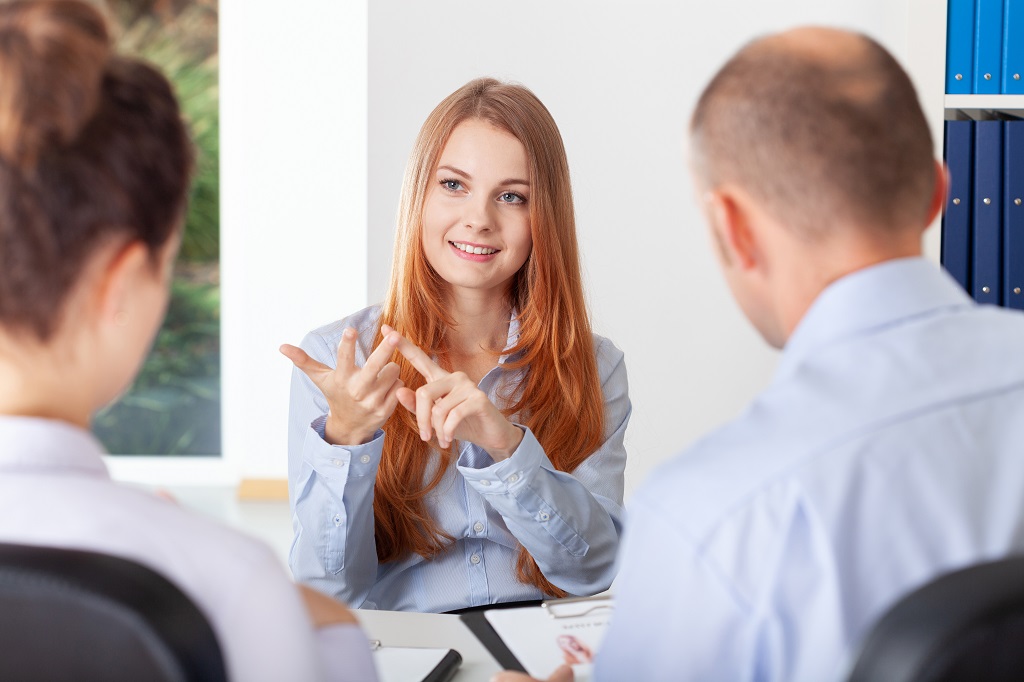 A Female Job Seeker Asking Questions To A Panel Of Interviewers