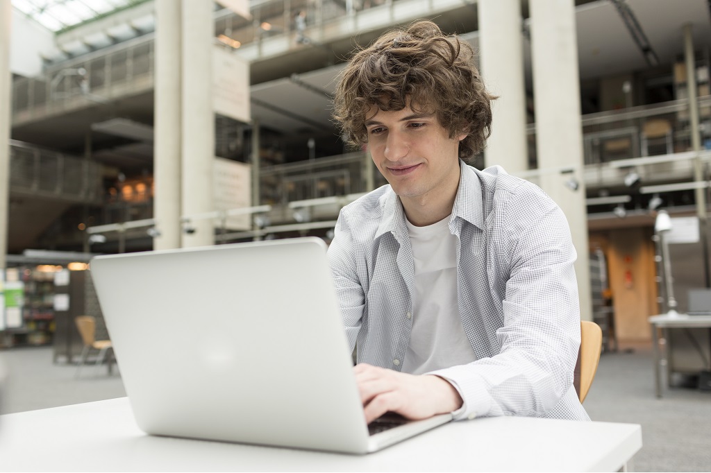 A Job Seeker Using A Laptop To Research Hybrid Workplace Strategies