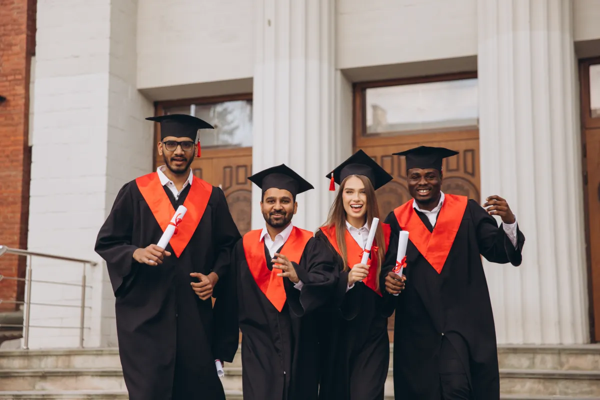 group of happy graduates celebrating success holding diplomas outside university building