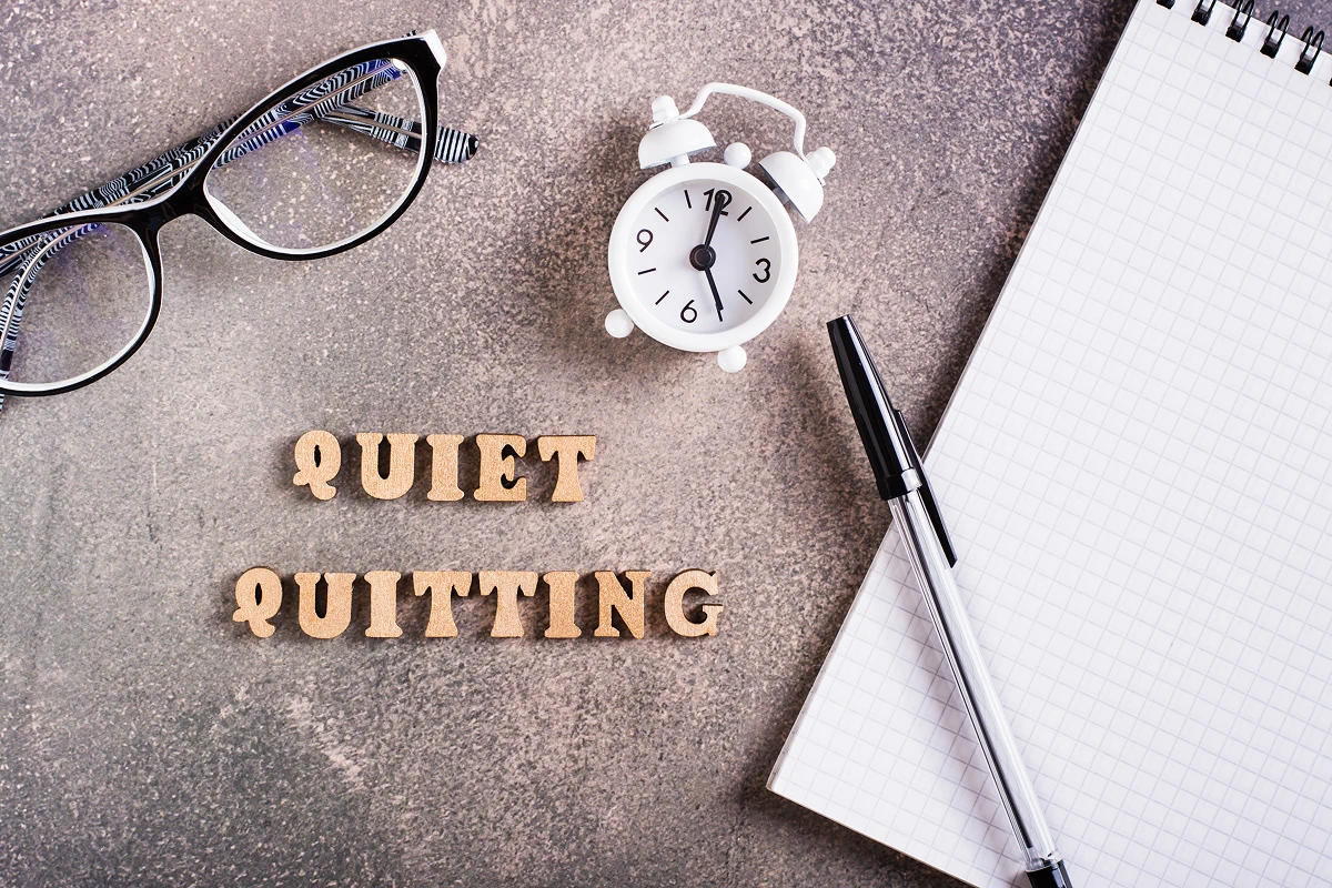 quiet quitting concept wooden letters stationery and alarm clock top view