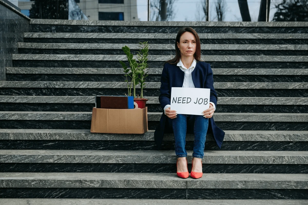 job seeker on stairs holding an unemployment sign