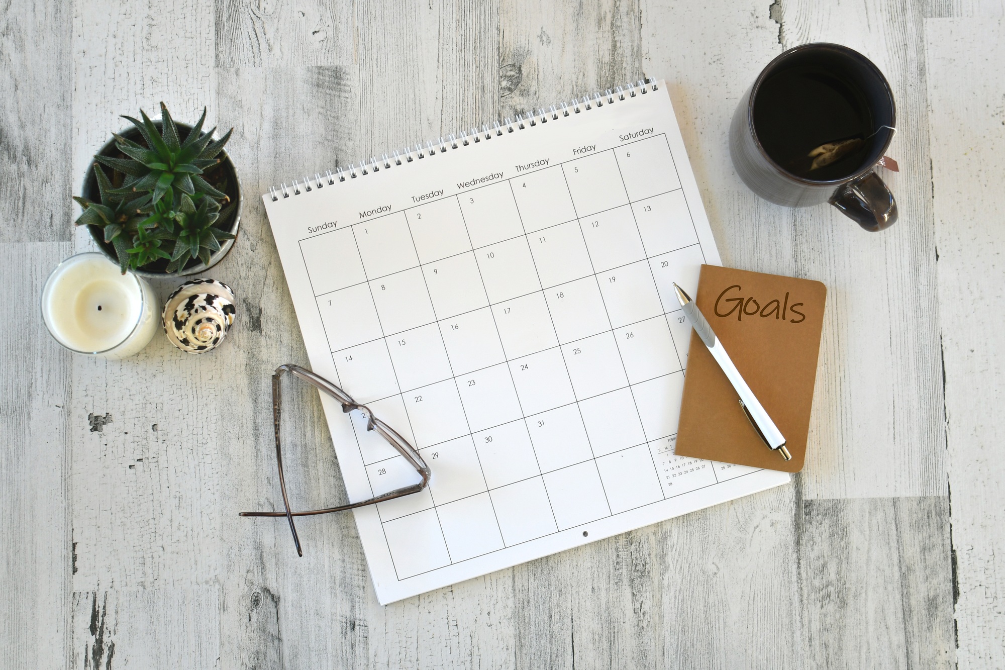 Overhead flat lay view of calendar goals notebook scheduling work personal appointments - blank year