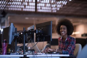professional using multiple computer monitors and a laptop