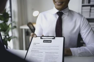 candidate handing over resume during interview to illustrate what is a resume in the hiring process