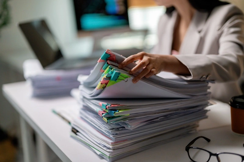 Employee Completing Paperwork To Highlight Administrative Skills For Resume