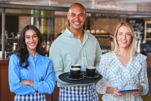 friendly café staff posing together representing teamwork in a server job description