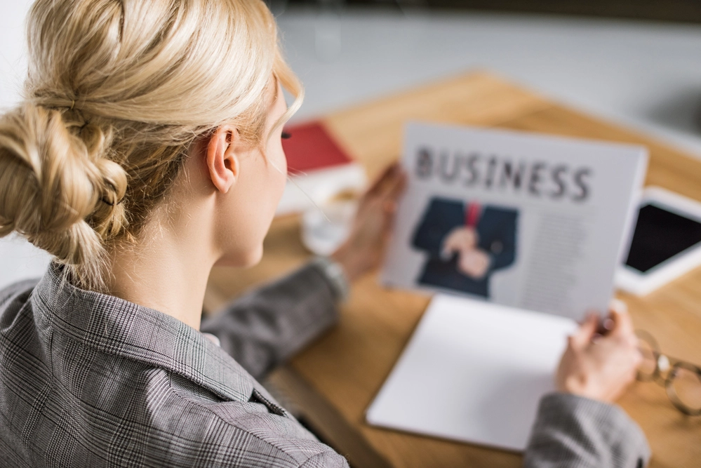 A Businesswoman Reading The Business Section Of A Newspaper To Hone Her Business And Commercial Acumen