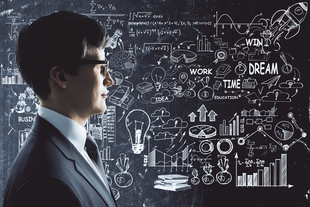 A Side Portrait Of A Professional With A Business Strategy Chalkboard Representing The Concept Of Critical Thinking With Examples