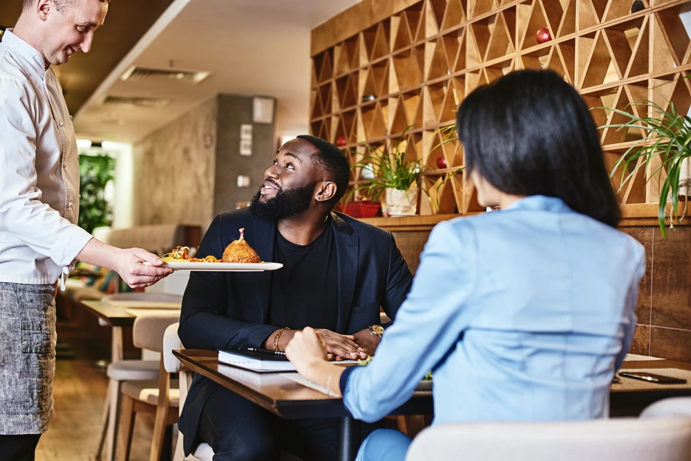 A Server Directly Asking Customers Their Feedback On Services Provided, Illustrating Great Customer Service.