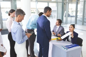 Rear view of diverse business people checking in at the job fair table.