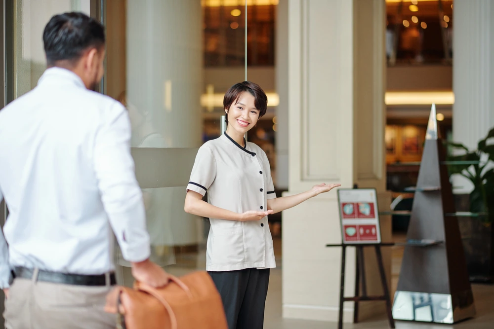 A Smiling Hotel Staff Offering Complimentary Upgrade To A Guest, Illustrating Great Customer Service.