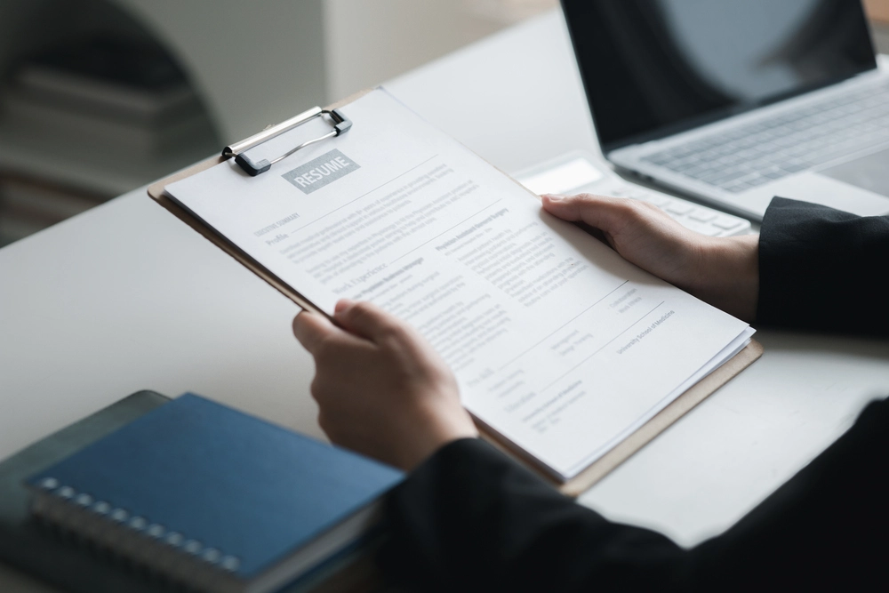 A View Of Two Hands Holding A Resume, Illustrating A Job Applicant Contemplating How To Write A Concise Resume Objective Statement