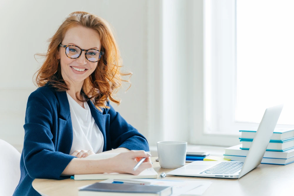 Smiling Woman Working At Desk With Laptop